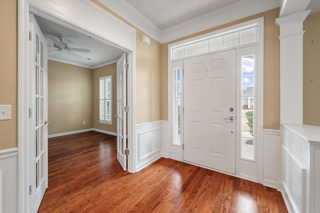 entryway featuring hardwood / wood-style flooring, crown molding, ceiling fan, and ornate columns