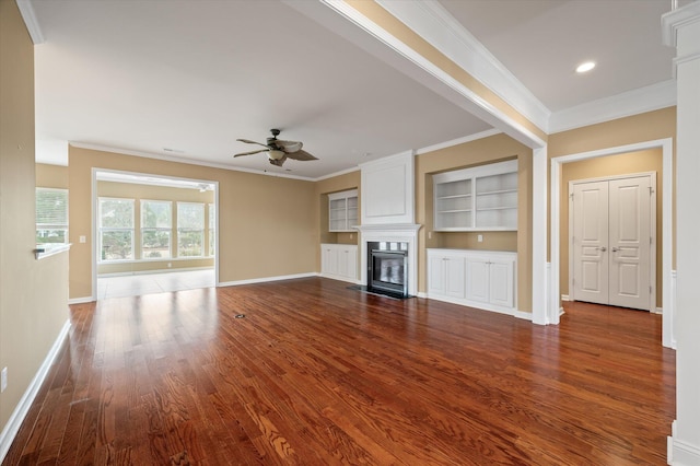 unfurnished living room with crown molding, ceiling fan, wood-type flooring, and built in shelves