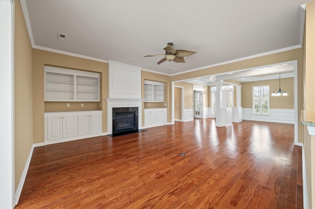 unfurnished living room featuring crown molding, hardwood / wood-style flooring, ceiling fan with notable chandelier, and built in shelves