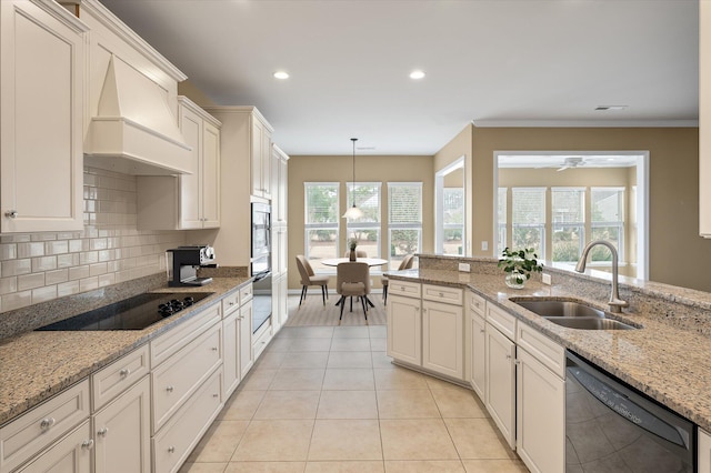 kitchen featuring sink, custom exhaust hood, light stone counters, pendant lighting, and black appliances