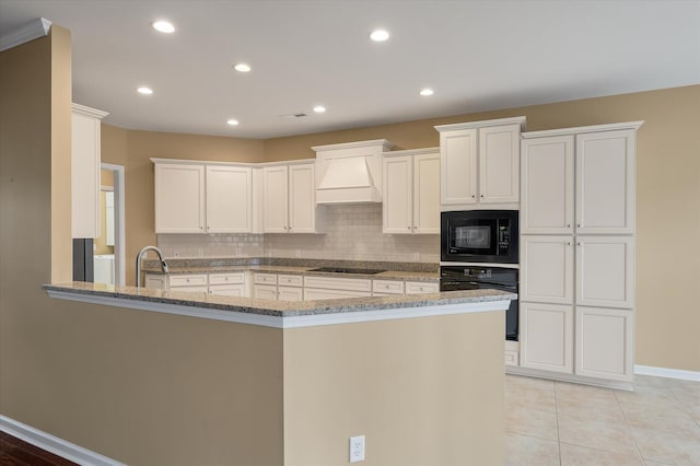 kitchen with black appliances, white cabinetry, custom exhaust hood, light stone counters, and kitchen peninsula