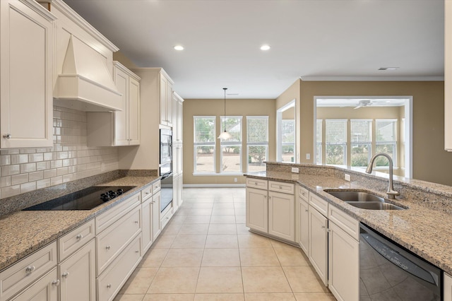 kitchen with sink, pendant lighting, light stone counters, and black appliances