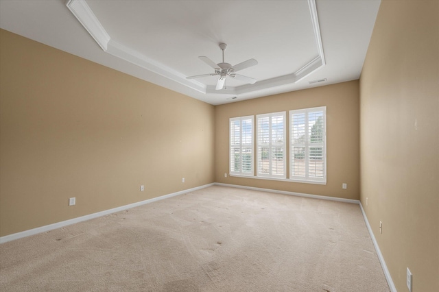 carpeted empty room with a raised ceiling and ceiling fan