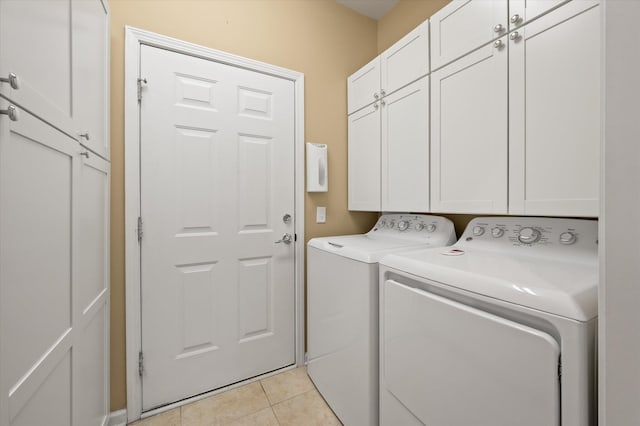 clothes washing area with cabinets, washing machine and clothes dryer, and light tile patterned flooring