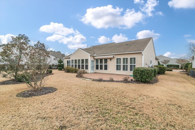 rear view of house featuring central AC unit and a lawn