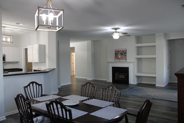 dining area with a textured ceiling, dark wood-type flooring, ceiling fan with notable chandelier, and built in shelves