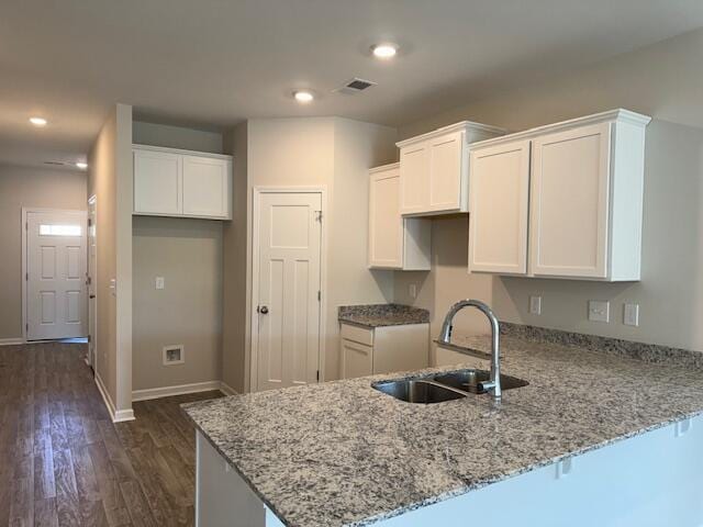 kitchen featuring sink, dark hardwood / wood-style floors, white cabinetry, light stone counters, and kitchen peninsula