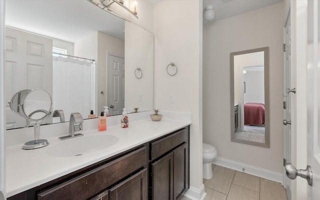 bathroom with vanity, toilet, and baseboards