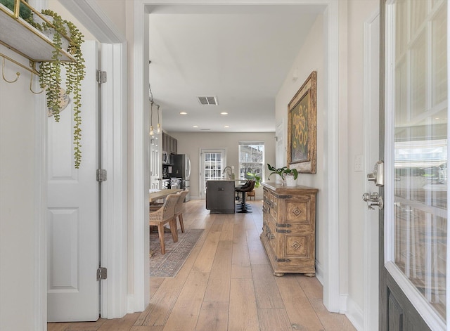 corridor with visible vents, recessed lighting, baseboards, and light wood-style floors