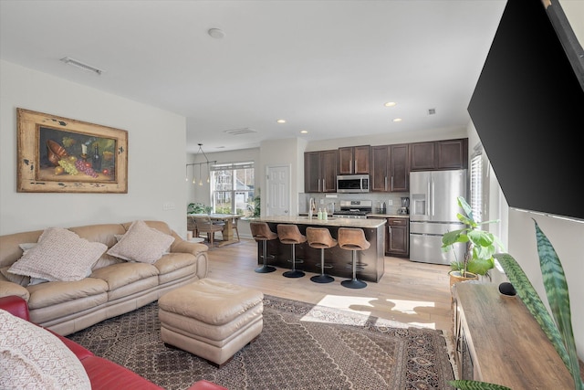 living area with light wood-type flooring, visible vents, and recessed lighting