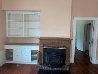 unfurnished living room featuring a wood stove and dark hardwood / wood-style floors