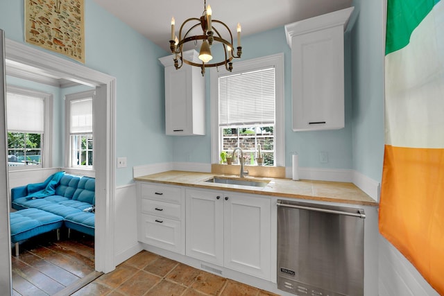 kitchen featuring light tile flooring, white cabinetry, a chandelier, stainless steel dishwasher, and sink