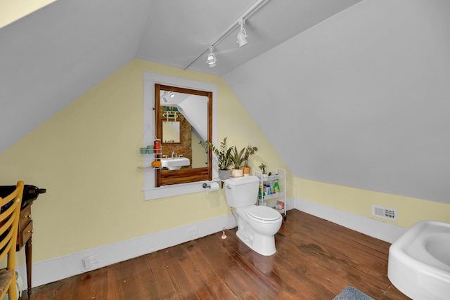 bathroom featuring lofted ceiling, toilet, vanity, hardwood / wood-style flooring, and track lighting