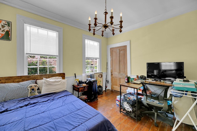 bedroom with crown molding, hardwood / wood-style flooring, and an inviting chandelier