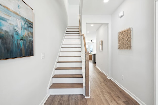 stairs with hardwood / wood-style floors and ceiling fan