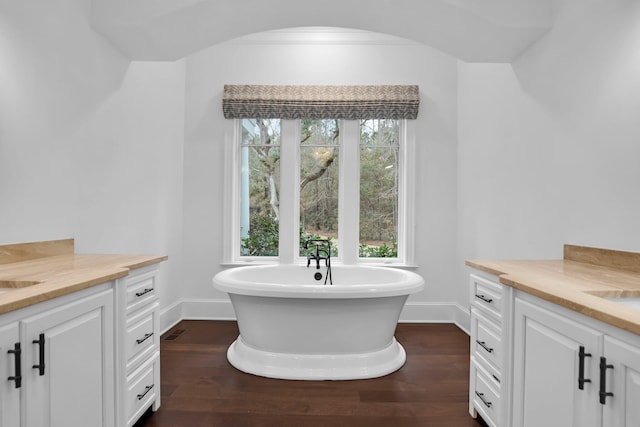 bathroom with hardwood / wood-style floors, vanity, and a washtub