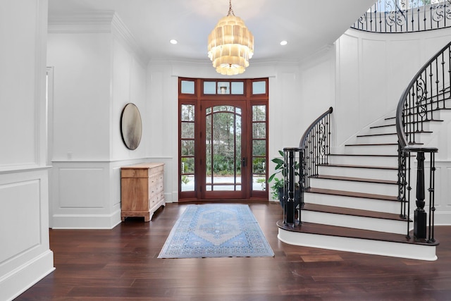 foyer entrance featuring an inviting chandelier, dark wood-type flooring, and ornamental molding