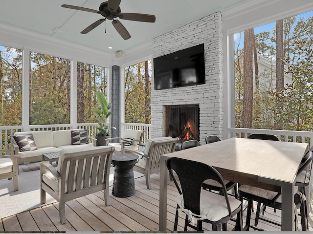 sunroom featuring ceiling fan and an outdoor stone fireplace