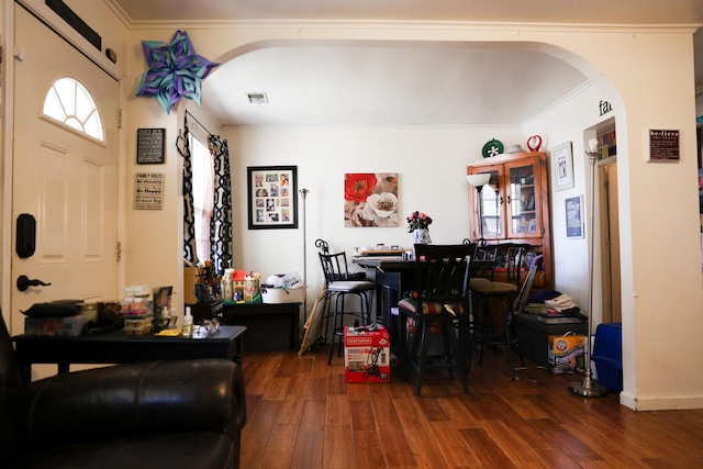 interior space featuring arched walkways, wood finished floors, and ornamental molding