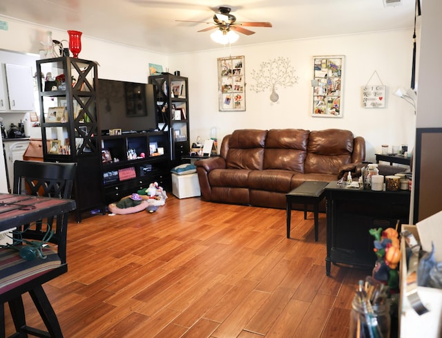 living room with light wood-style flooring, visible vents, and ceiling fan