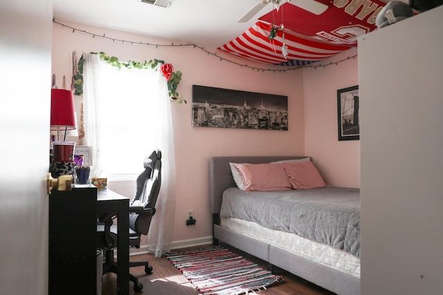 bedroom with a ceiling fan, wood finished floors, visible vents, and baseboards