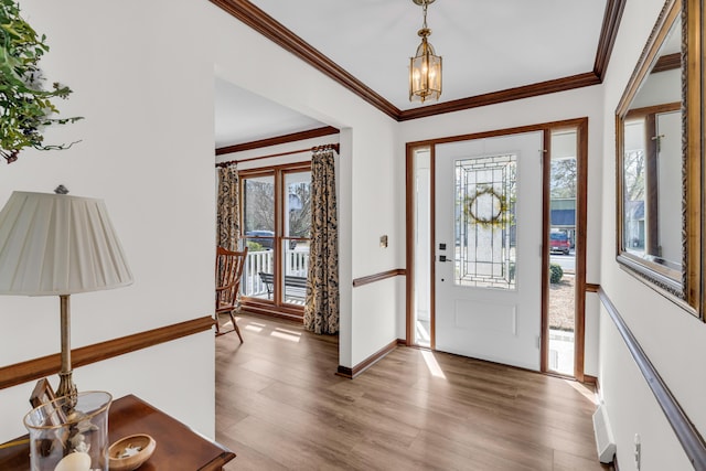 foyer with baseboards, a chandelier, wood finished floors, and crown molding