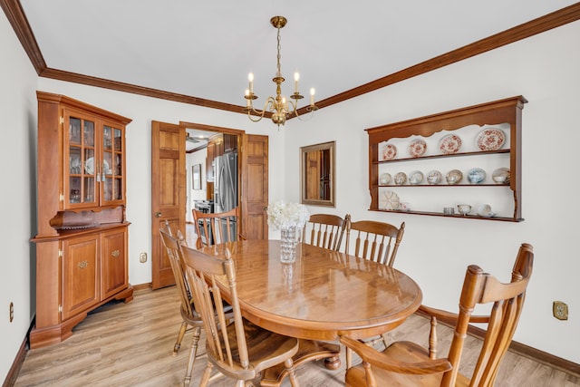 dining room featuring light wood-style floors, a chandelier, crown molding, and baseboards