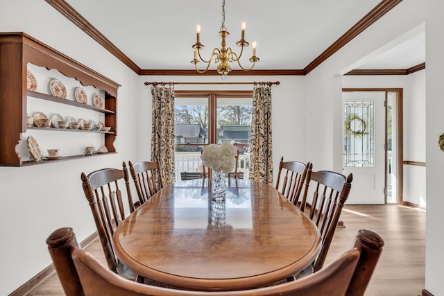 dining room with ornamental molding, a notable chandelier, baseboards, and wood finished floors