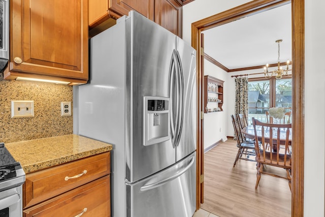 kitchen featuring ornamental molding, brown cabinets, stainless steel appliances, a chandelier, and backsplash