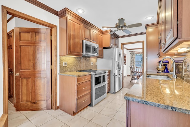 kitchen with stainless steel appliances, light stone counters, a sink, and crown molding