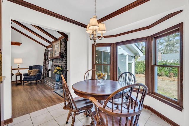 dining space with vaulted ceiling, a healthy amount of sunlight, crown molding, and a fireplace