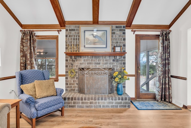 living area featuring a fireplace, visible vents, wood finished floors, beamed ceiling, and baseboards