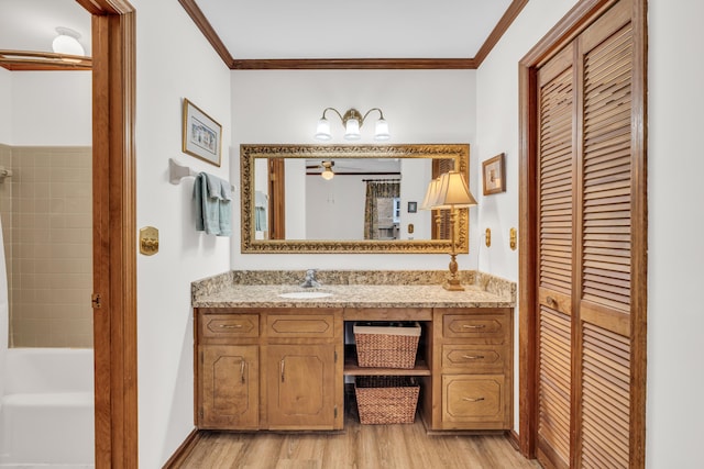 full bath featuring wood finished floors, vanity, baseboards, ornamental molding, and a closet