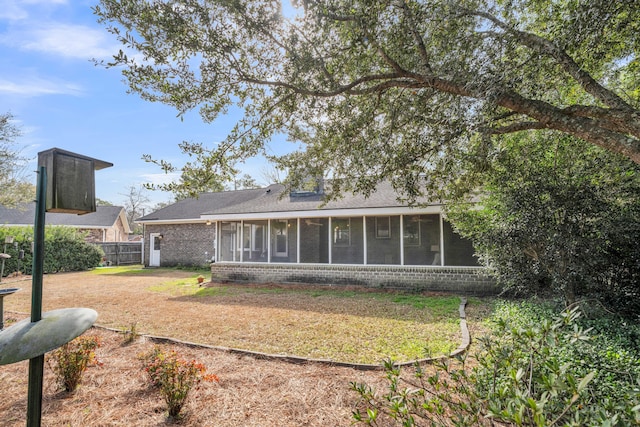 back of house with brick siding, a lawn, fence, and a sunroom