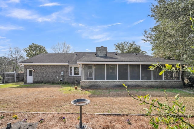 rear view of property with brick siding, a shingled roof, fence, a sunroom, and a chimney