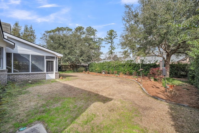 view of yard with driveway, a sunroom, and fence