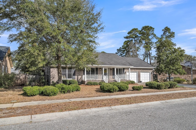 view of front of home featuring brick siding, covered porch, an attached garage, fence, and driveway