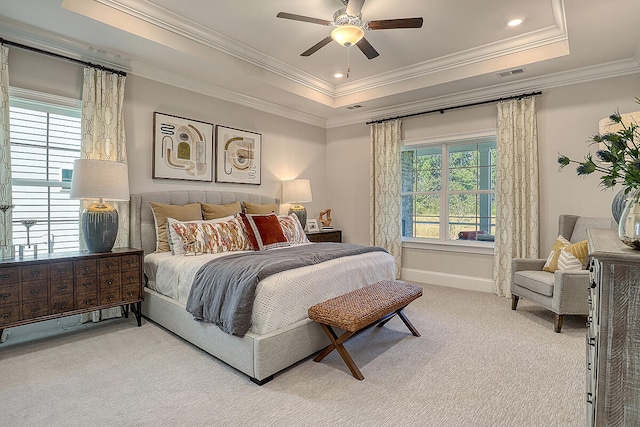 bedroom featuring a tray ceiling, ornamental molding, light carpet, baseboards, and ceiling fan