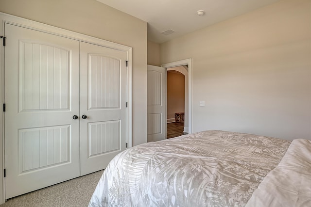 carpeted bedroom featuring a closet and arched walkways