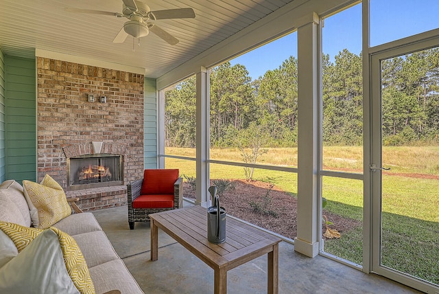 sunroom / solarium featuring a brick fireplace and a ceiling fan