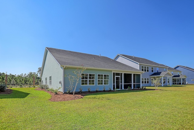 rear view of house featuring a yard and a sunroom