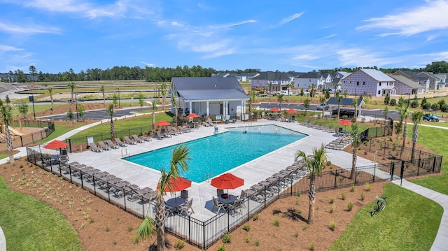 community pool featuring fence, a patio area, and a residential view