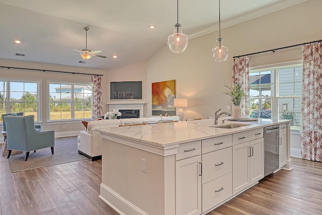 kitchen with a sink, dishwasher, open floor plan, ceiling fan, and a center island with sink