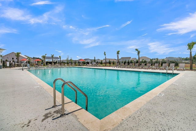community pool featuring fence, a residential view, and a patio
