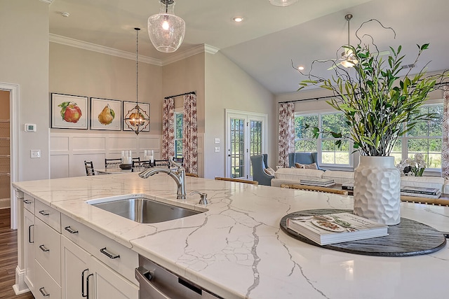 kitchen with a sink, white cabinets, decorative light fixtures, light stone counters, and high vaulted ceiling
