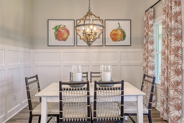 dining space featuring a decorative wall, a chandelier, dark wood-type flooring, and wainscoting