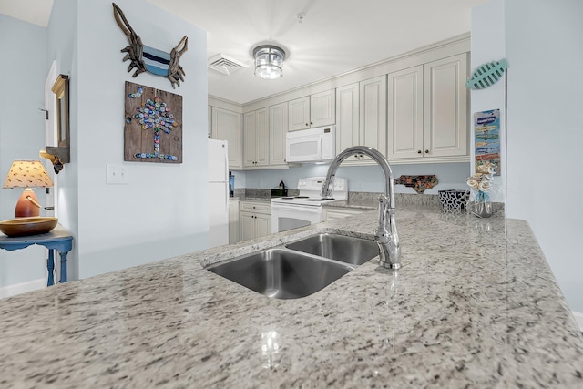 kitchen with light stone countertops, sink, and white appliances