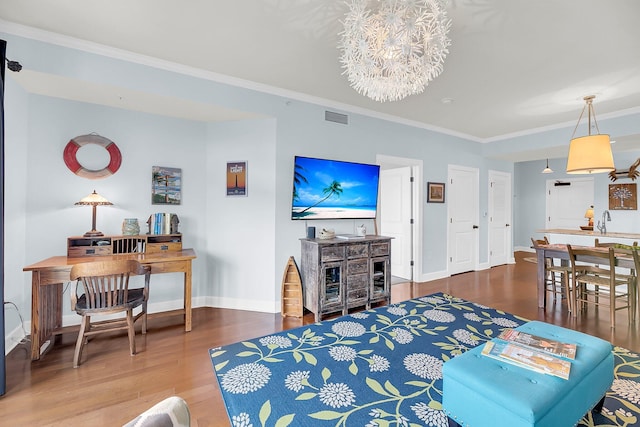 living room featuring a notable chandelier, wood-type flooring, and ornamental molding