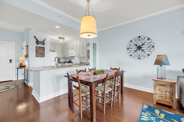 dining area featuring ornamental molding, sink, and dark hardwood / wood-style floors