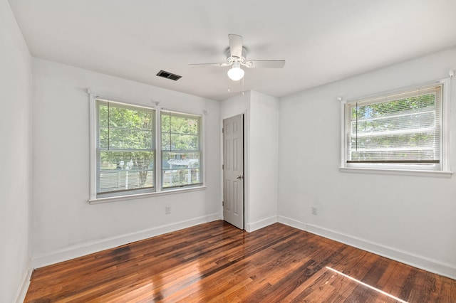 empty room with a wealth of natural light, ceiling fan, and dark wood-type flooring